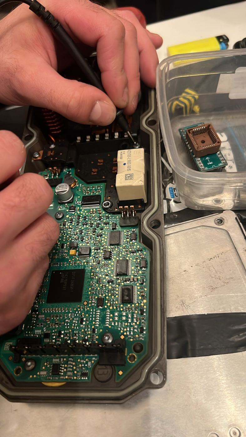 Technician probing an opened ECU circuit board